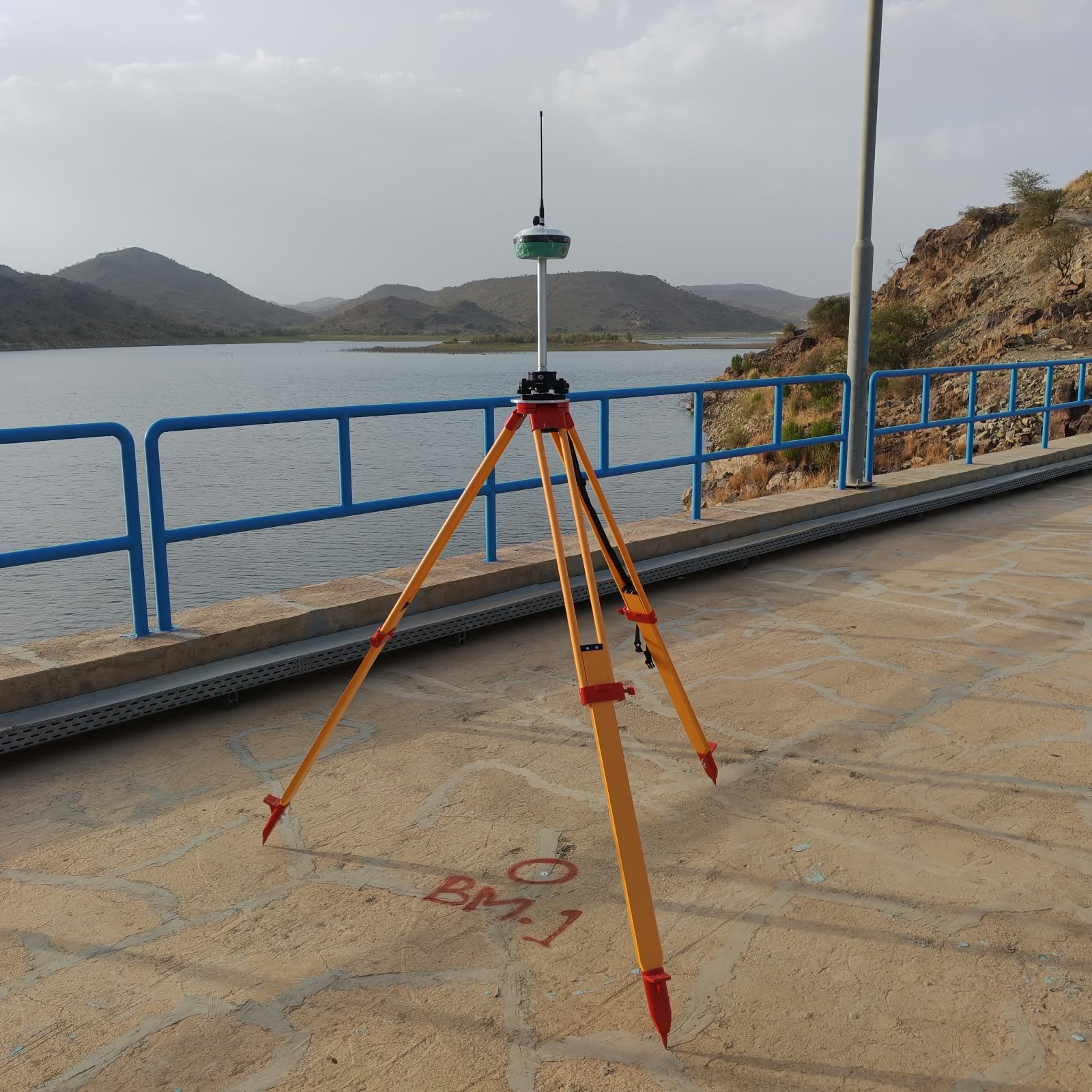 جهاز استقبال GNSS مثبت على حامل ثلاثي بالقرب من بحيرة ومنطقة جبلية